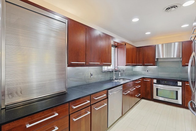 kitchen featuring sink, decorative backsplash, wall chimney exhaust hood, and appliances with stainless steel finishes