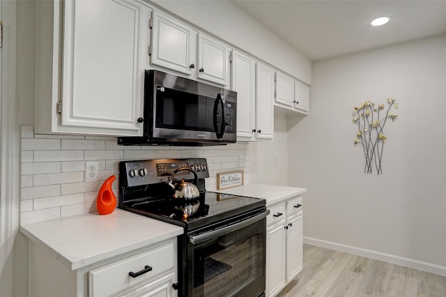 kitchen with backsplash, black electric range, light hardwood / wood-style flooring, and white cabinets