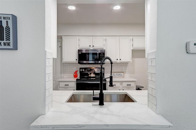 kitchen with white cabinetry, sink, decorative backsplash, light stone counters, and black range with electric stovetop