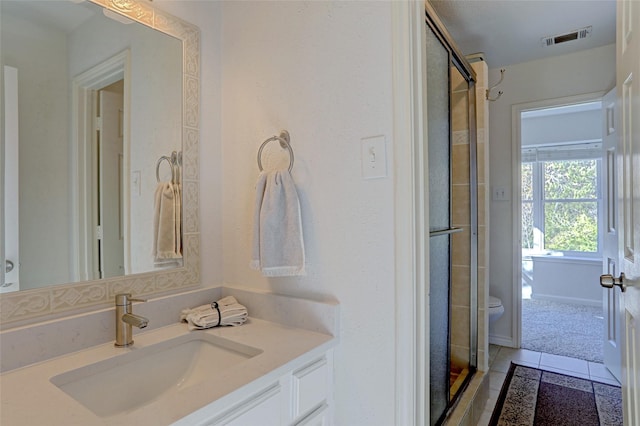 bathroom featuring tile patterned floors, vanity, toilet, and a shower with door