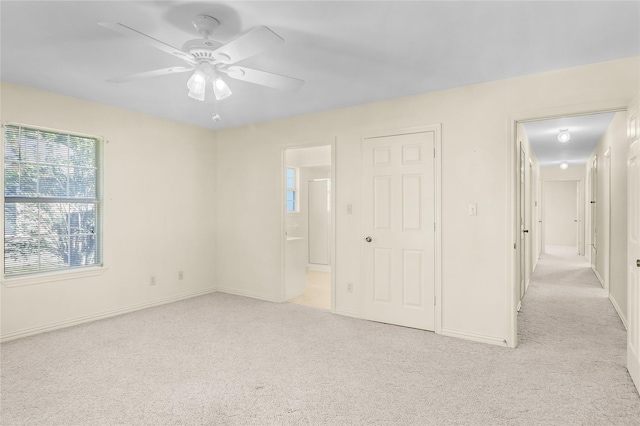 unfurnished bedroom with light carpet, ceiling fan, and ensuite bathroom