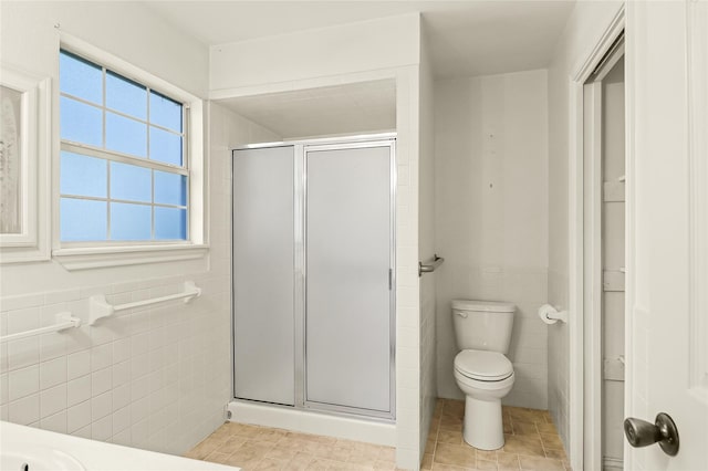 bathroom with toilet, an enclosed shower, and tile walls