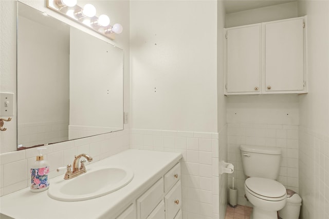 bathroom with vanity, toilet, and tile walls