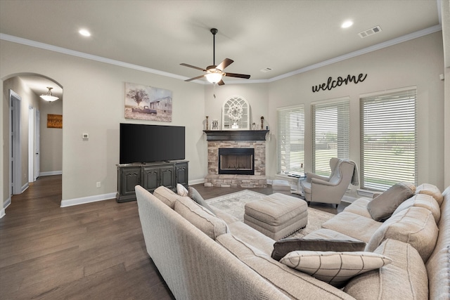 living room featuring ornamental molding, dark hardwood / wood-style flooring, and a stone fireplace