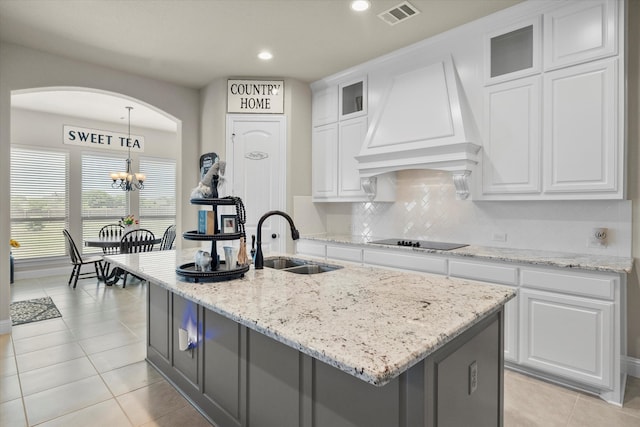 kitchen with sink, premium range hood, white cabinetry, an island with sink, and black electric cooktop