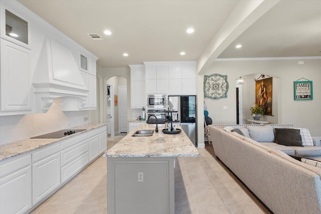 kitchen featuring sink, white cabinetry, appliances with stainless steel finishes, light stone countertops, and a kitchen island with sink