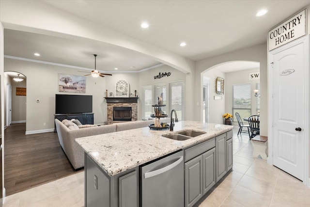 kitchen with sink, gray cabinets, dishwasher, light stone countertops, and an island with sink