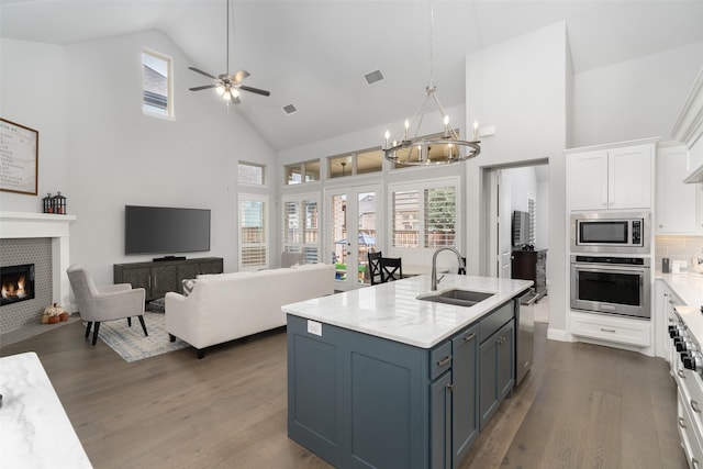 kitchen with sink, decorative light fixtures, appliances with stainless steel finishes, a fireplace, and white cabinets