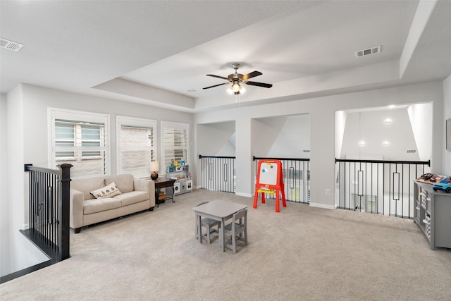 living room featuring light colored carpet, a raised ceiling, and ceiling fan