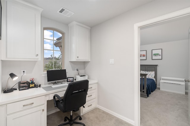 home office featuring built in desk and light carpet