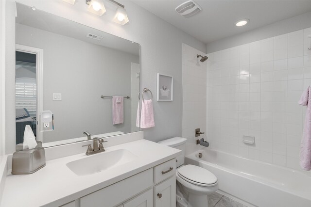 full bathroom with vanity, tiled shower / bath combo, tile patterned floors, and toilet