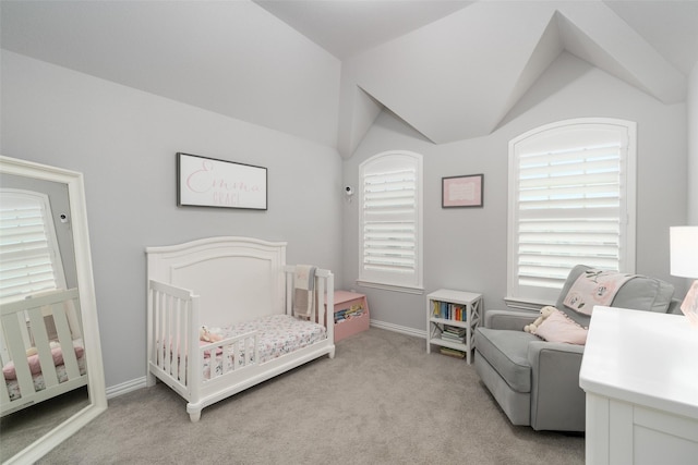 bedroom with a crib, vaulted ceiling, and light colored carpet