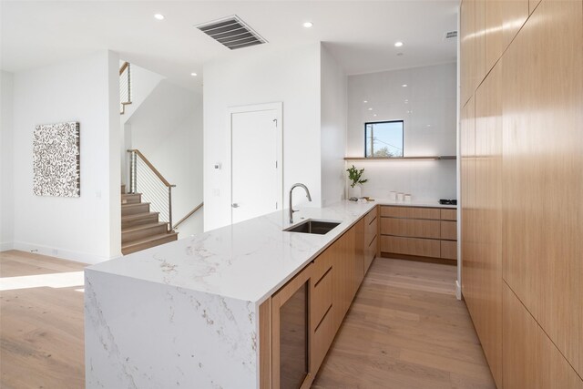 kitchen featuring light hardwood / wood-style floors, sink, light stone counters, and kitchen peninsula