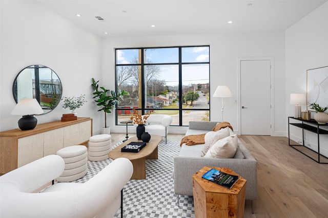 living area featuring baseboards, visible vents, wood finished floors, and recessed lighting