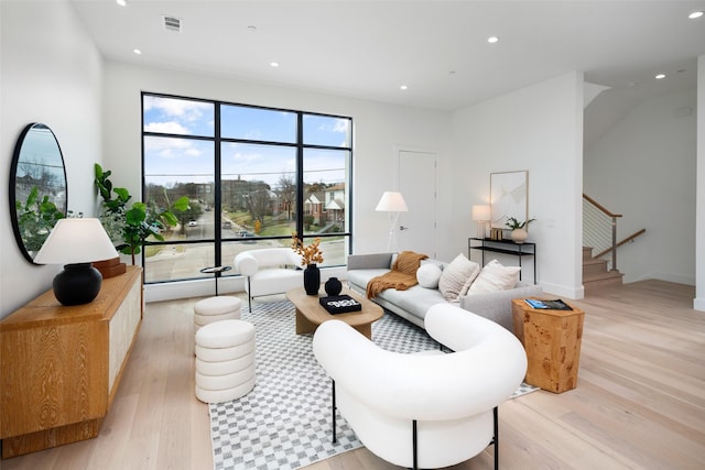 living area featuring stairs, light wood-type flooring, visible vents, and recessed lighting