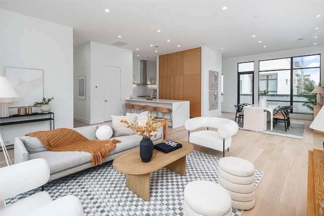 living room featuring light wood finished floors, baseboards, visible vents, and recessed lighting