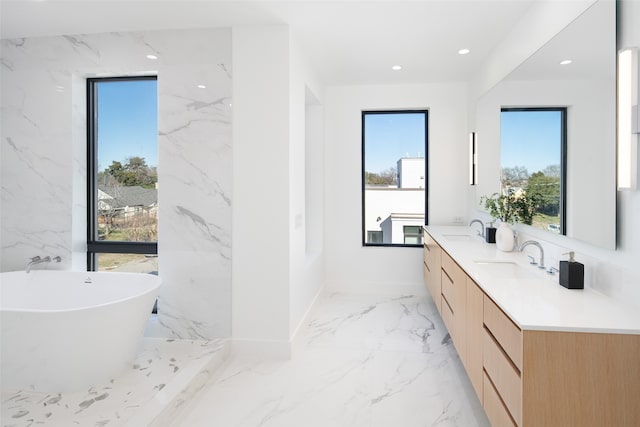 bathroom with vanity, a healthy amount of sunlight, and a tub to relax in