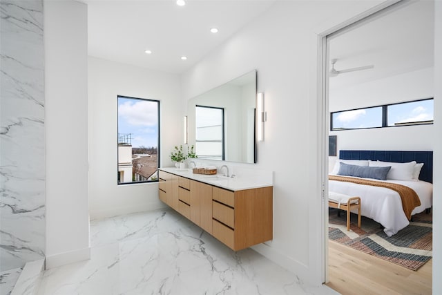 ensuite bathroom featuring baseboards, connected bathroom, marble finish floor, vanity, and recessed lighting