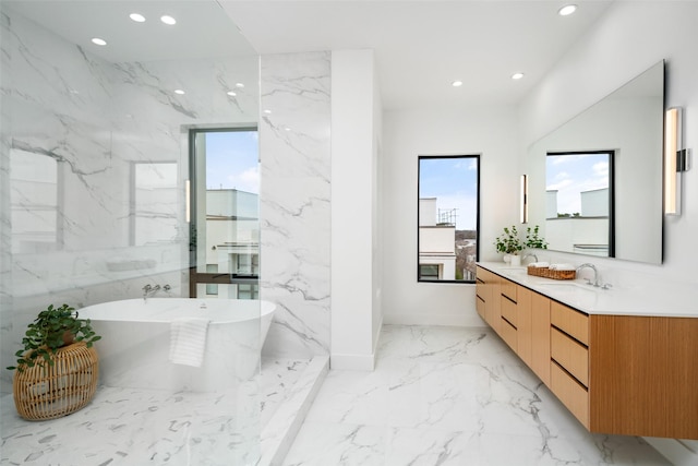 bathroom featuring recessed lighting, marble finish floor, a freestanding bath, and stone wall