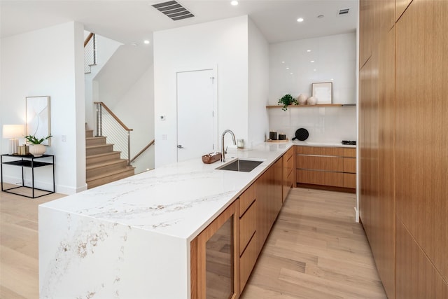 kitchen featuring visible vents, modern cabinets, a peninsula, light wood-style floors, and a sink