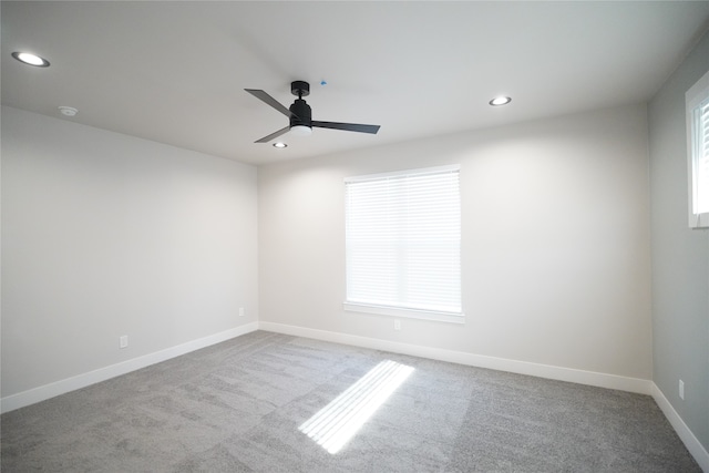 unfurnished room with a wealth of natural light, ceiling fan, and light colored carpet