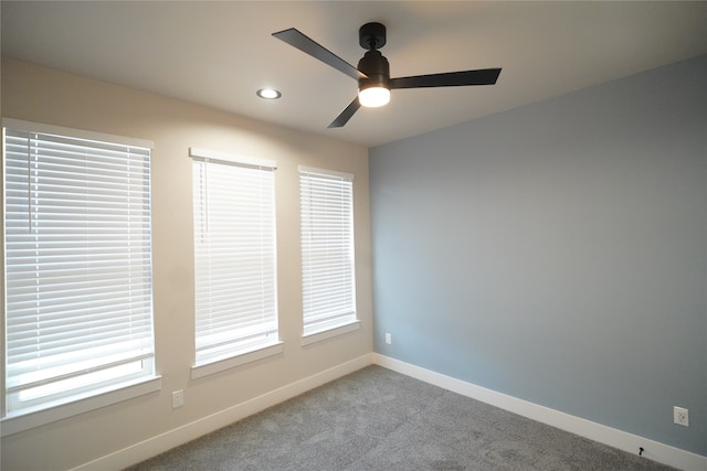 carpeted spare room featuring ceiling fan and a wealth of natural light