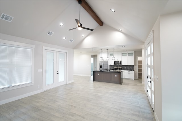 kitchen with light wood-type flooring, stainless steel appliances, a kitchen island with sink, decorative light fixtures, and white cabinets