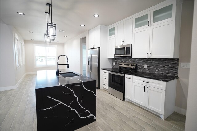 kitchen with a kitchen island with sink, sink, white cabinets, and appliances with stainless steel finishes