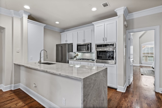 kitchen featuring light stone countertops, white cabinetry, sink, stainless steel appliances, and kitchen peninsula