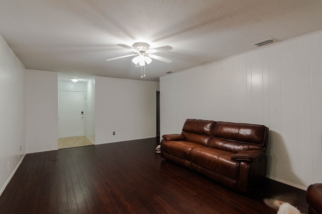 living room with dark hardwood / wood-style floors, ceiling fan, and a textured ceiling