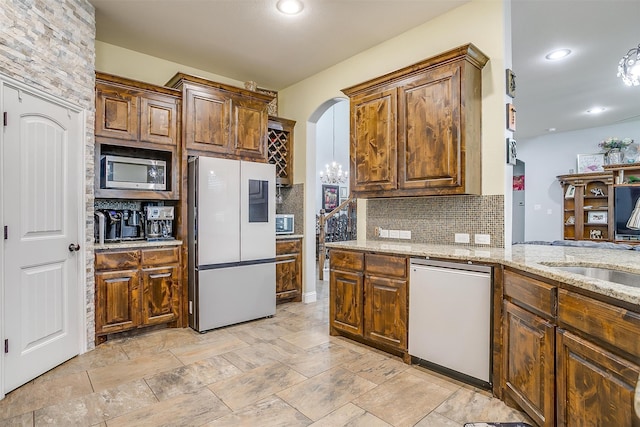 kitchen with backsplash, sink, light stone countertops, and stainless steel appliances