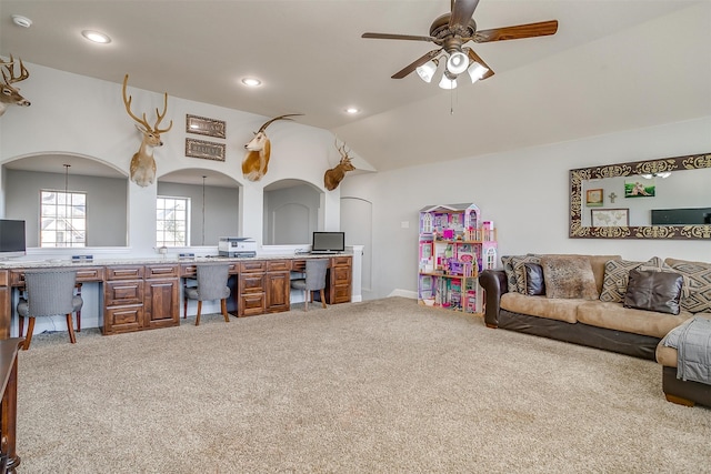 carpeted living room featuring built in desk, vaulted ceiling, and ceiling fan