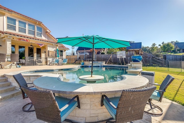 view of pool with a lawn, a patio area, pool water feature, and an outdoor bar