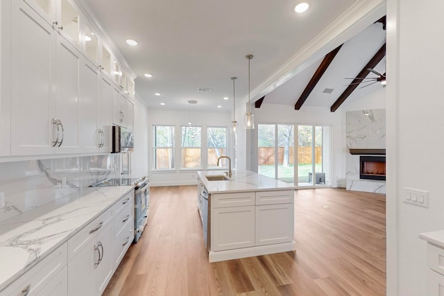 kitchen featuring stainless steel appliances, sink, white cabinets, and a fireplace