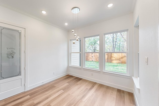 unfurnished dining area featuring ornamental molding and light hardwood / wood-style flooring