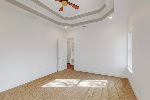 carpeted spare room with crown molding, a tray ceiling, and ceiling fan