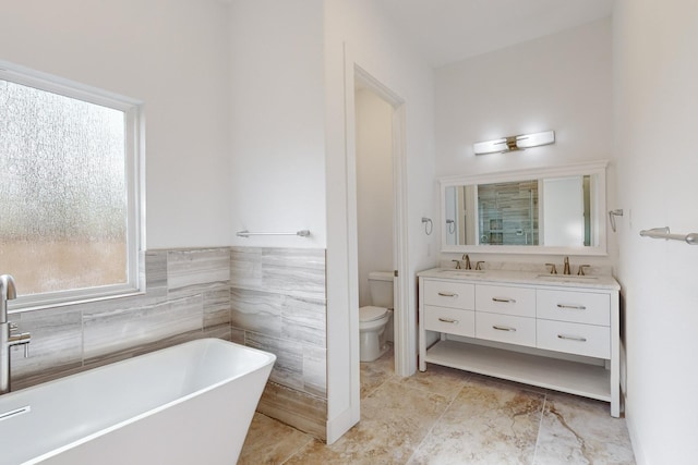 bathroom featuring vanity, toilet, a bathing tub, and tile walls