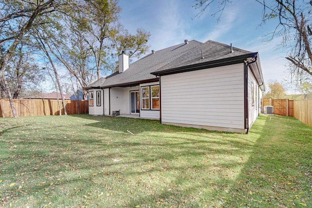 rear view of house featuring a lawn and central AC