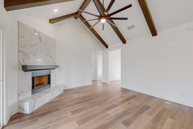 unfurnished living room featuring high vaulted ceiling, light hardwood / wood-style floors, a premium fireplace, and beamed ceiling