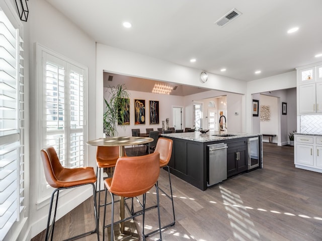 kitchen with white cabinets, a center island with sink, stainless steel dishwasher, and dark hardwood / wood-style floors