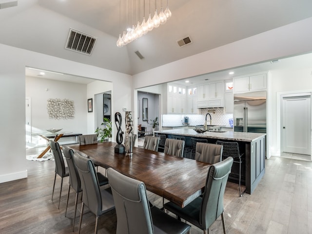 dining area featuring vaulted ceiling, light hardwood / wood-style flooring, and sink