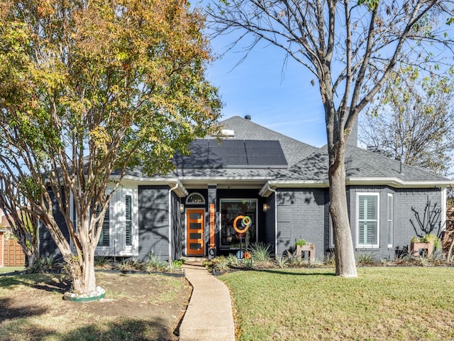 bungalow-style home with a front yard and solar panels