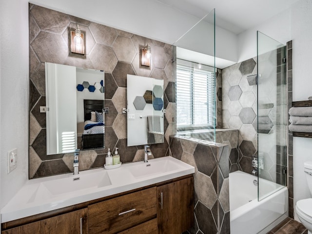 full bathroom featuring tiled shower / bath combo, toilet, tile walls, and vanity