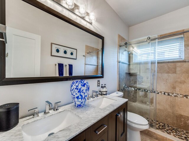 bathroom featuring tile patterned flooring, vanity, toilet, and a shower with shower door