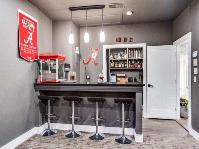 bar featuring hardwood / wood-style flooring and hanging light fixtures