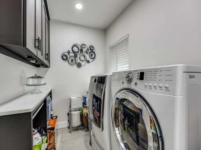 clothes washing area featuring cabinets, light tile patterned floors, and washing machine and dryer