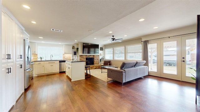 living room featuring ceiling fan, sink, dark hardwood / wood-style flooring, and a fireplace