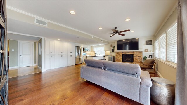 living room with built in shelves, ornamental molding, dark hardwood / wood-style floors, and a fireplace