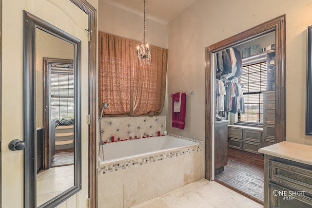 bathroom featuring vanity, a relaxing tiled tub, and a chandelier