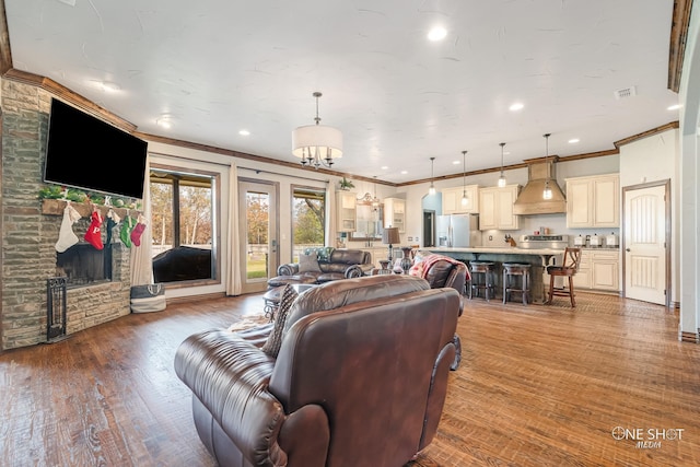 living room featuring crown molding, wood-type flooring, and a fireplace